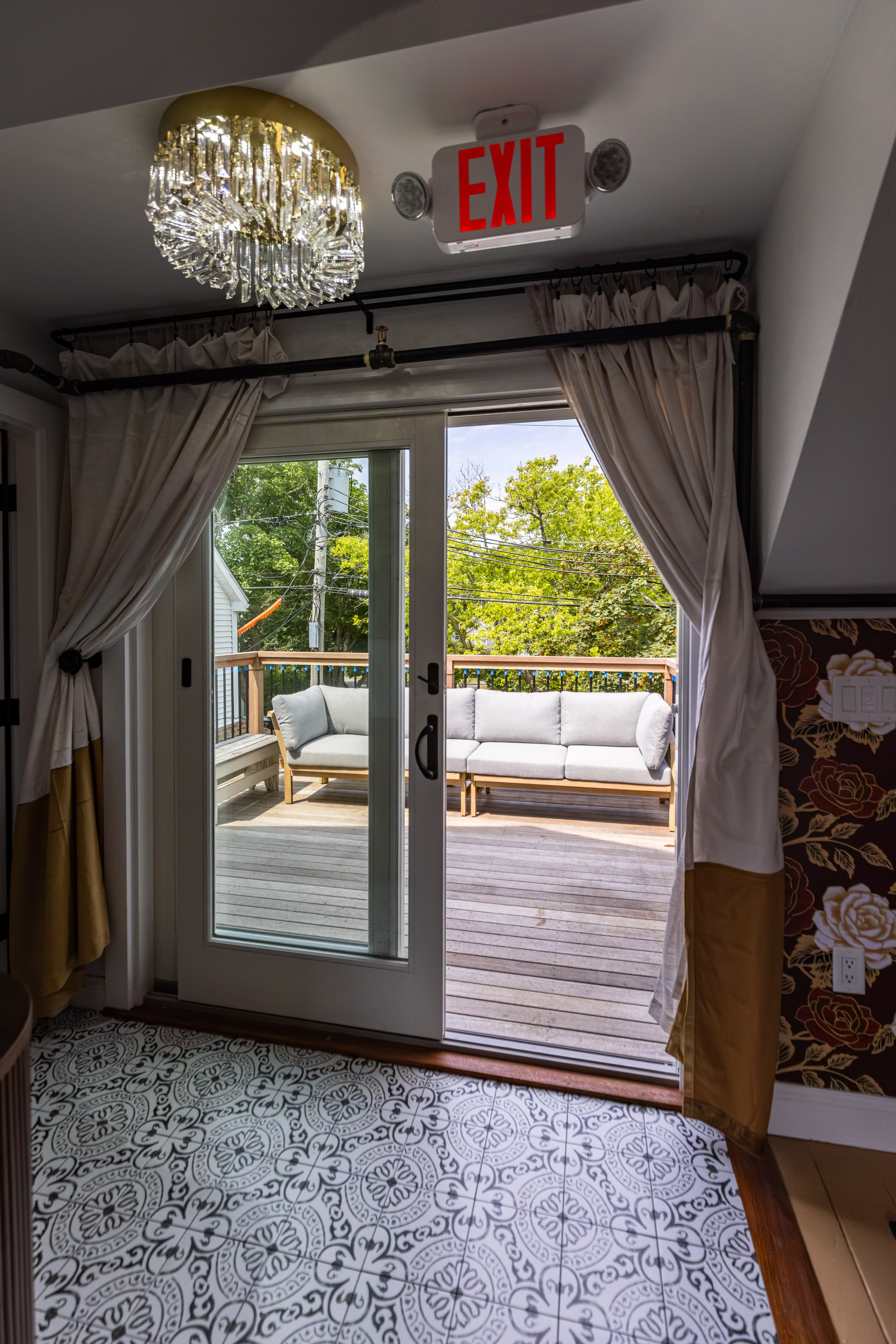A doorway leads to a deck with outdoor seating and a chandelier above.
