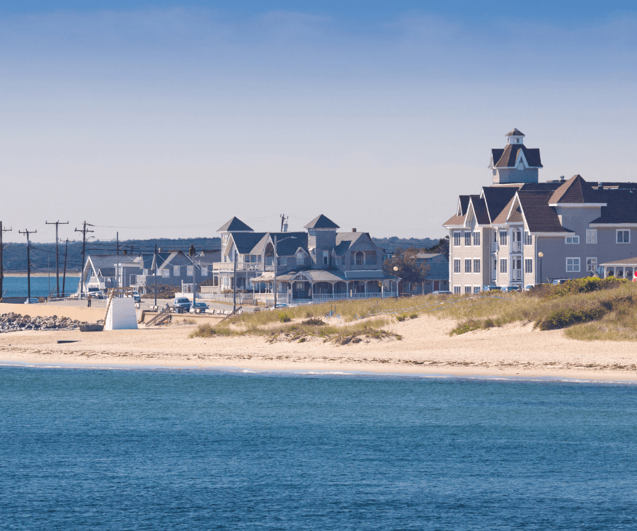 Coastal view featuring houses along a sandy beach with calm water.