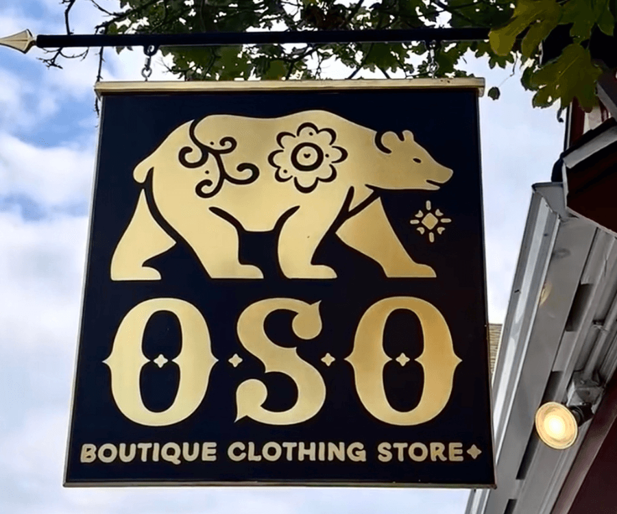 Sign for "OSO Boutique Clothing Store" featuring a gold bear design.