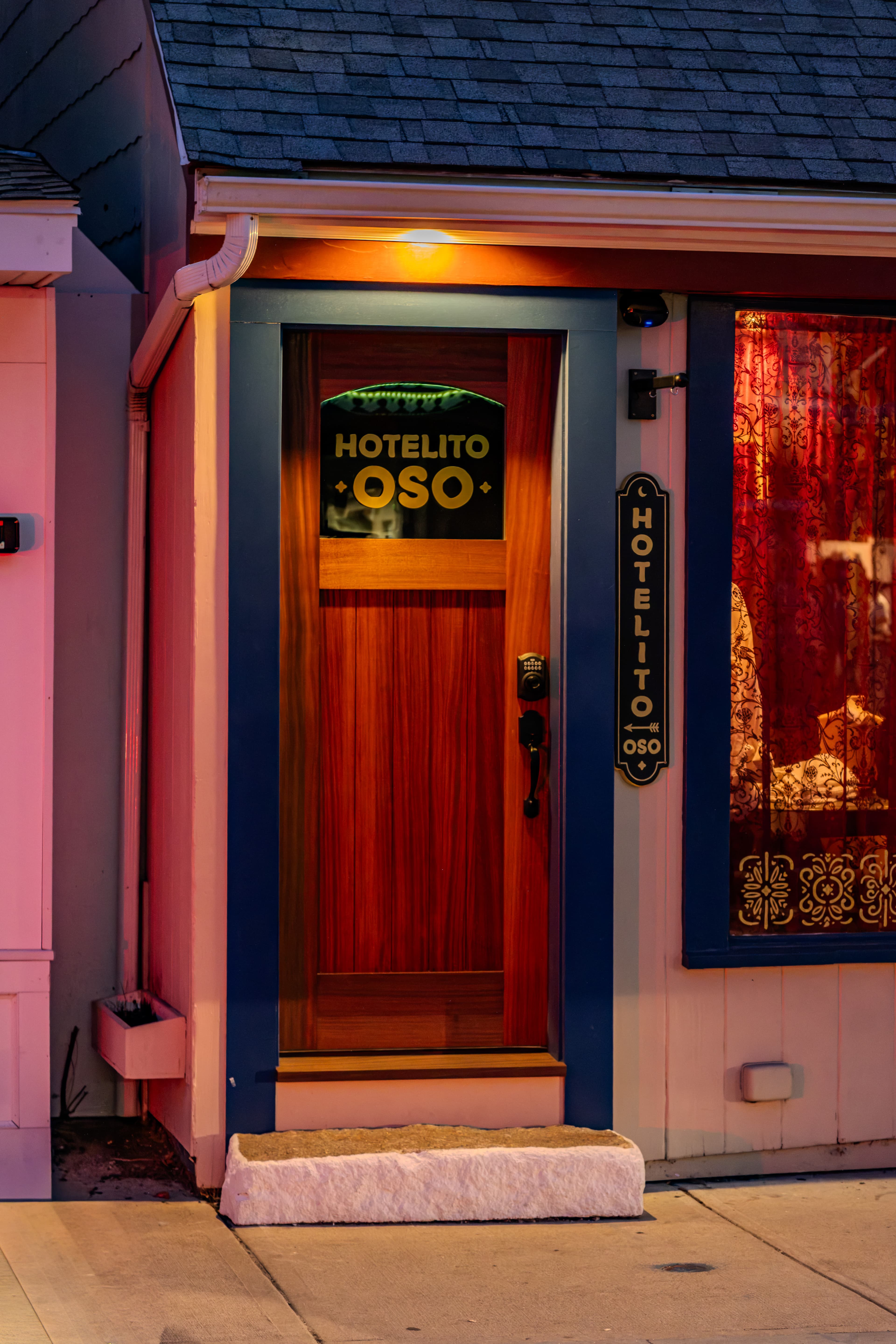 A warmly lit entrance of "Hotelito Oso" featuring a wooden door and decorative signage.