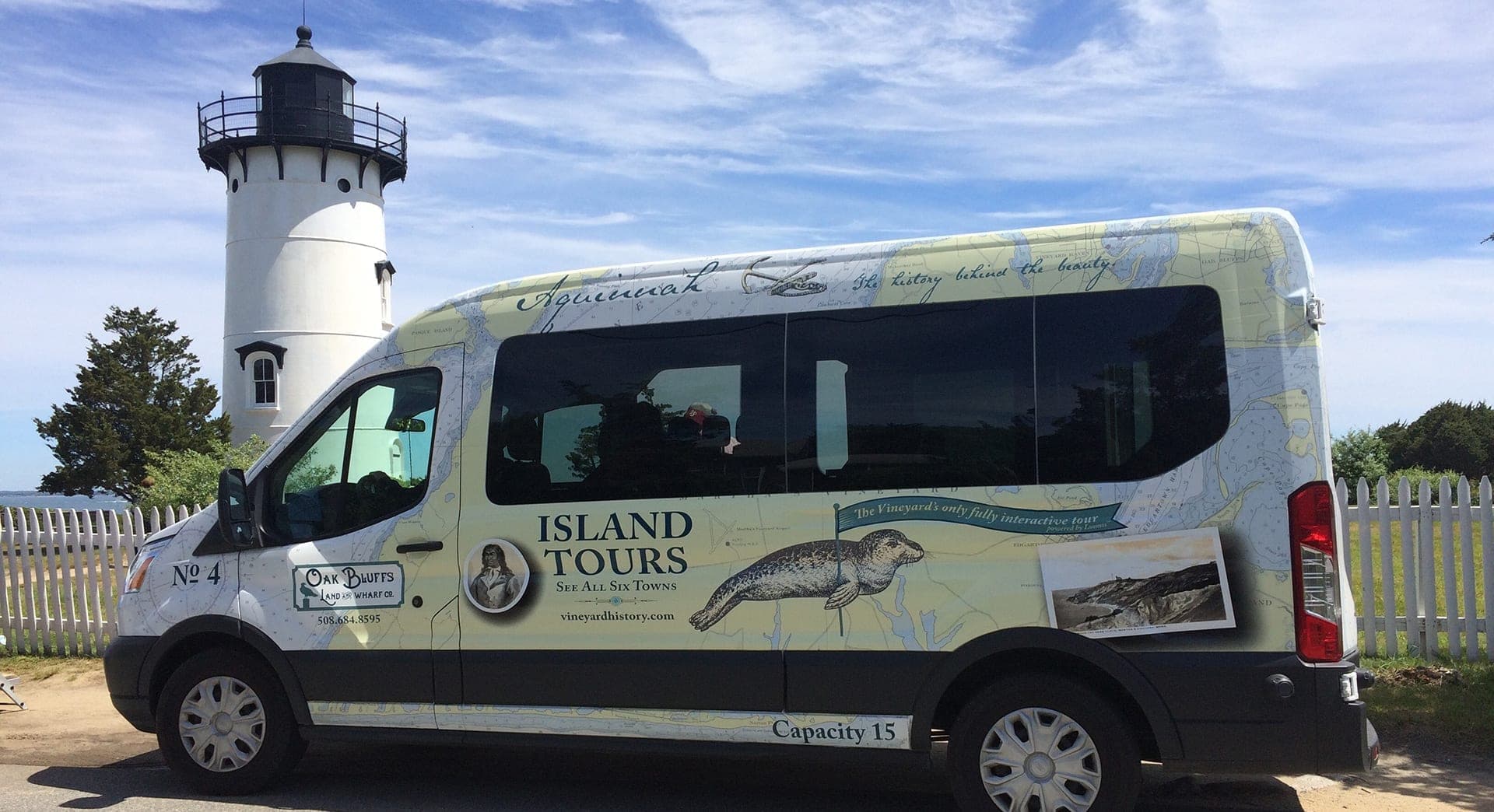 A tour van with "Island Tours" signage parked near a lighthouse.